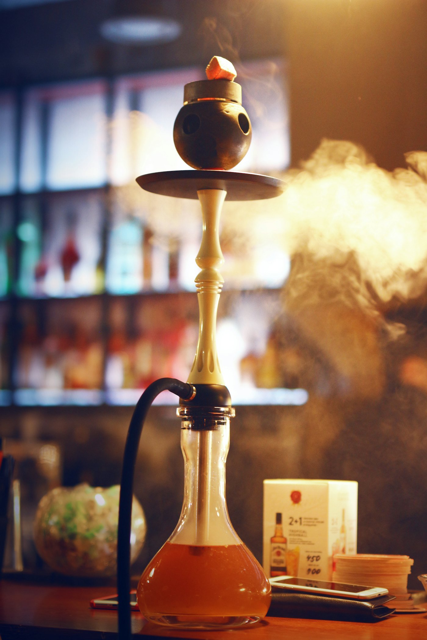 Shisha mit aufsteigendem Rauch in warmem Barlicht